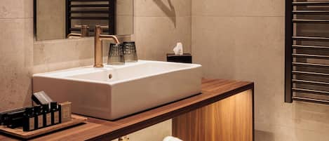 A modern bathroom with a large mirror, a white sink, and a wooden vanity.