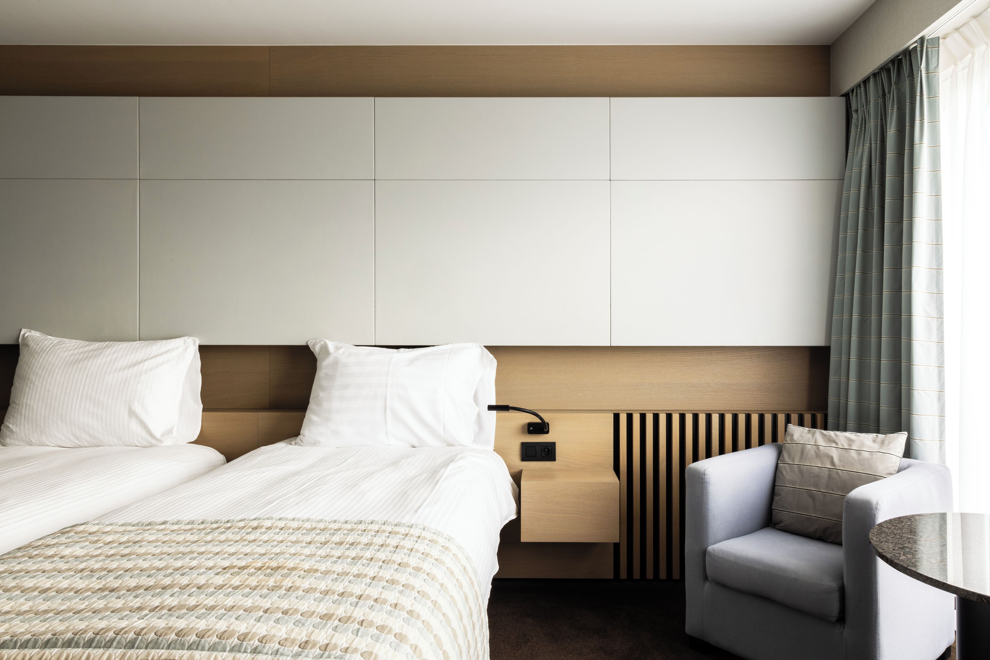 Een hotelkamer met een groot bed, een nachtkastje, een stoel en uitzicht op buiten.