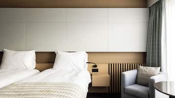 Een hotelkamer met een groot bed, een nachtkastje, een stoel en uitzicht op buiten.