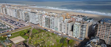 Un paisaje urbano costero con edificios altos, una playa y un puerto deportivo.