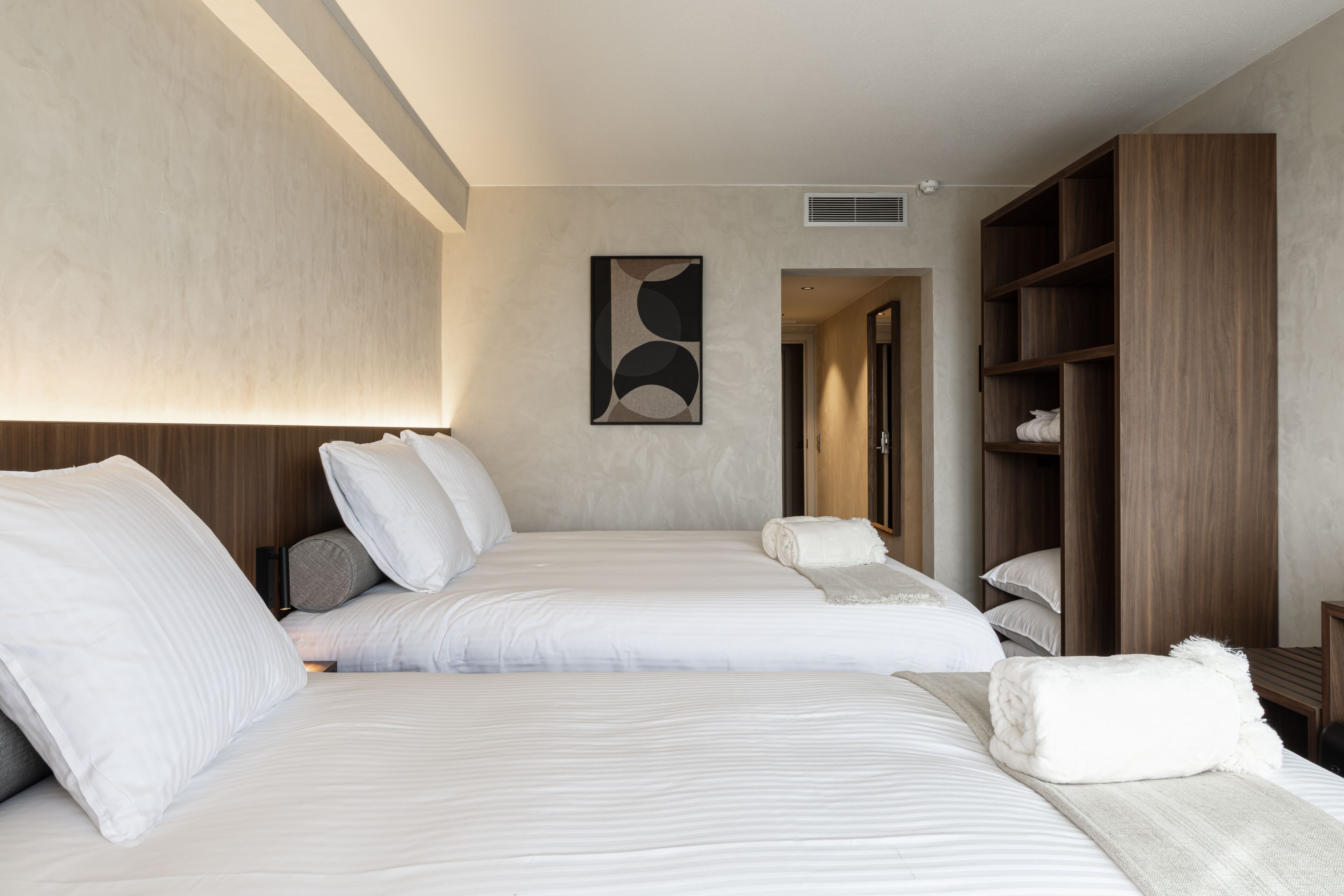 Habitación de hotel con dos camas, un armario grande y un cuadro en la pared.