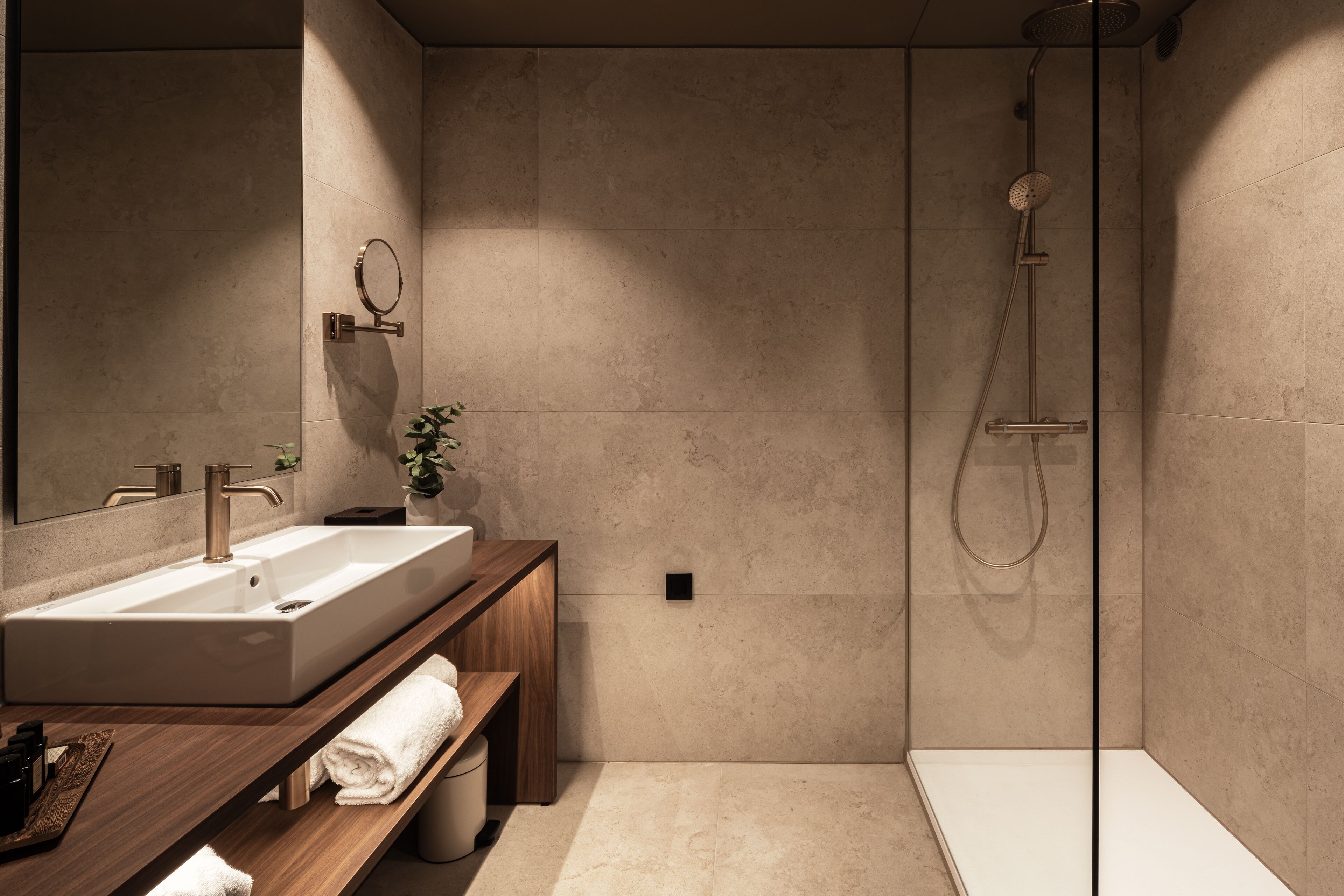 Un baño moderno con un lavamanos grande, espejo y ducha.