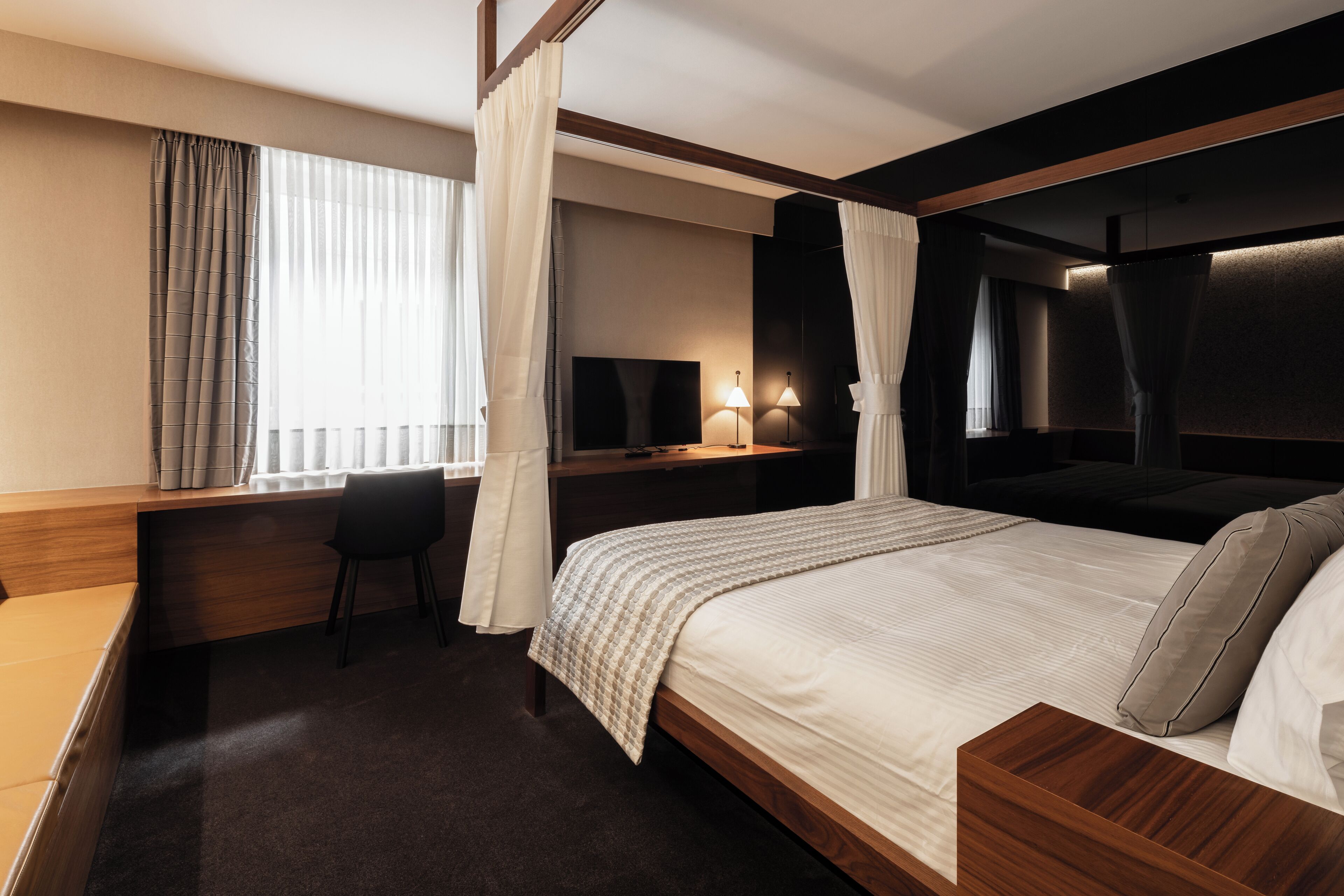 A modern hotel room with a large bed, a desk, a chair, and a television.