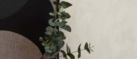 Un florero con una planta sobre una mesa de madera frente a una pared con arte abstracto.