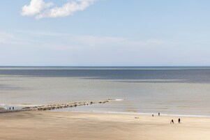 A wide beach with a calm sea and a clear sky.