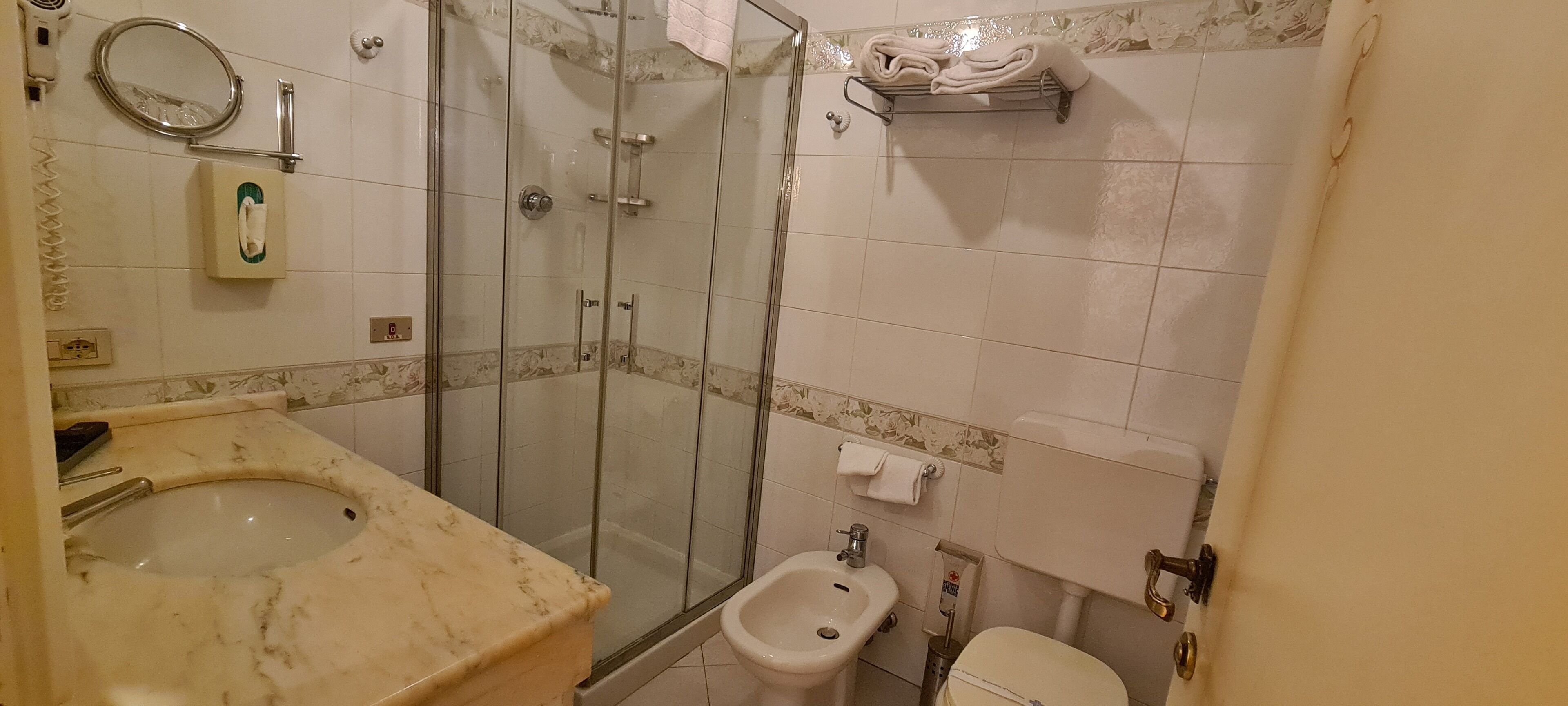 A bathroom with a glass-enclosed shower, a sink, a bidet, and a toilet.