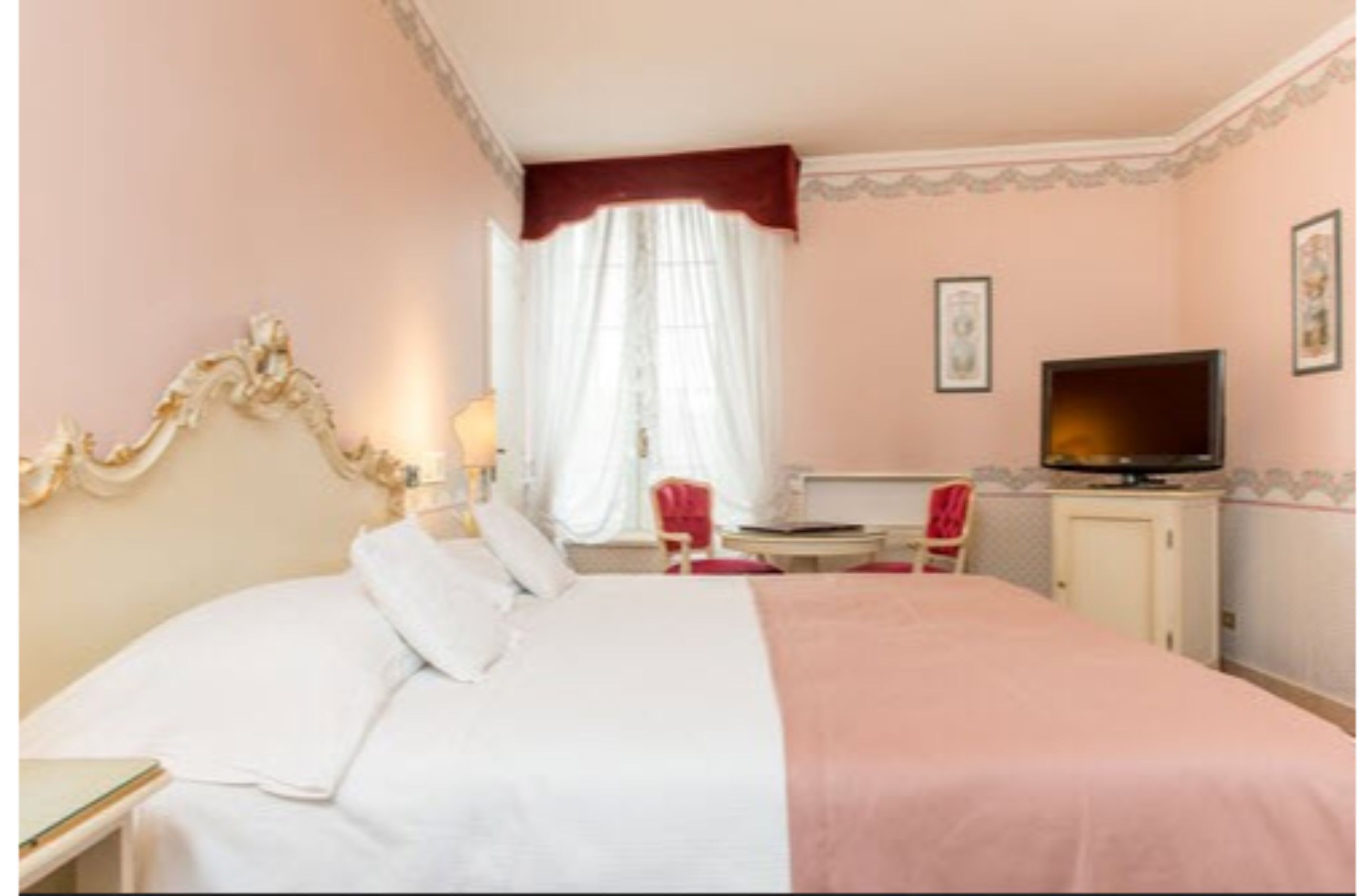 Une chambre d’hôtel avec un grand lit, une télévision, un bureau et une chaise.