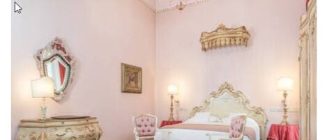 Une chambre à coucher avec un grand lit, deux chaises, une commode et un miroir.