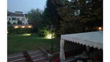 Ein Garten mit einem weißen Zelt, Pflanzgefäßen und einem Weg.