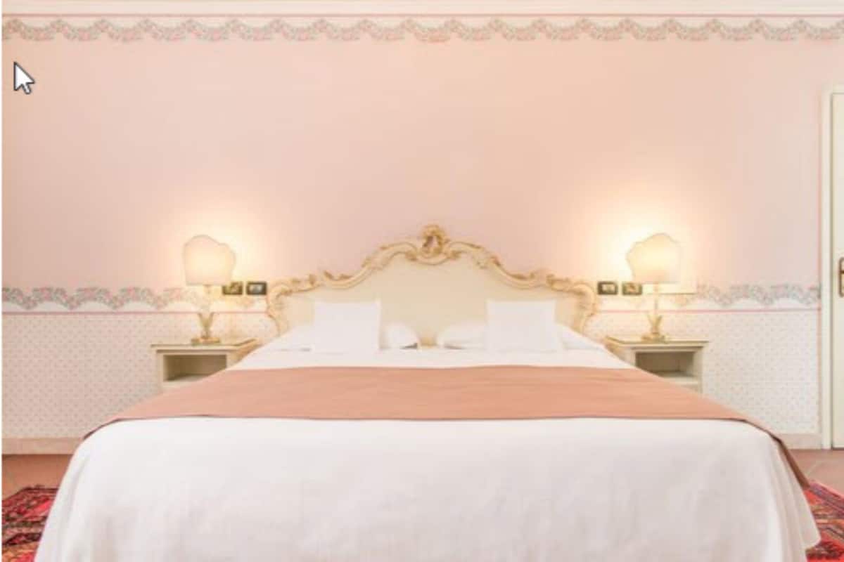 A hotel room with a large bed, two bedside tables with lamps, and a decorative headboard.