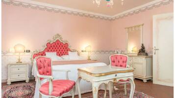 A bedroom with a large bed, two chairs, a dresser, and a mirror.