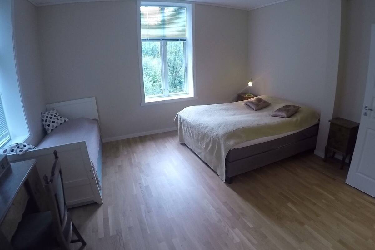 Una camera da letto con un letto, una scrivania, una sedia, una finestra e una porta.