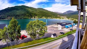 Vista de un lago con un edificio y coches aparcados en primer plano.