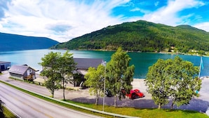 Una propiedad frente al lago, con una carretera, coches aparcados y un edificio de techo inclinado.