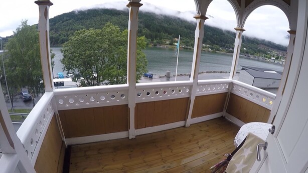 Un balcón de madera con vistas a un lago y montañas.