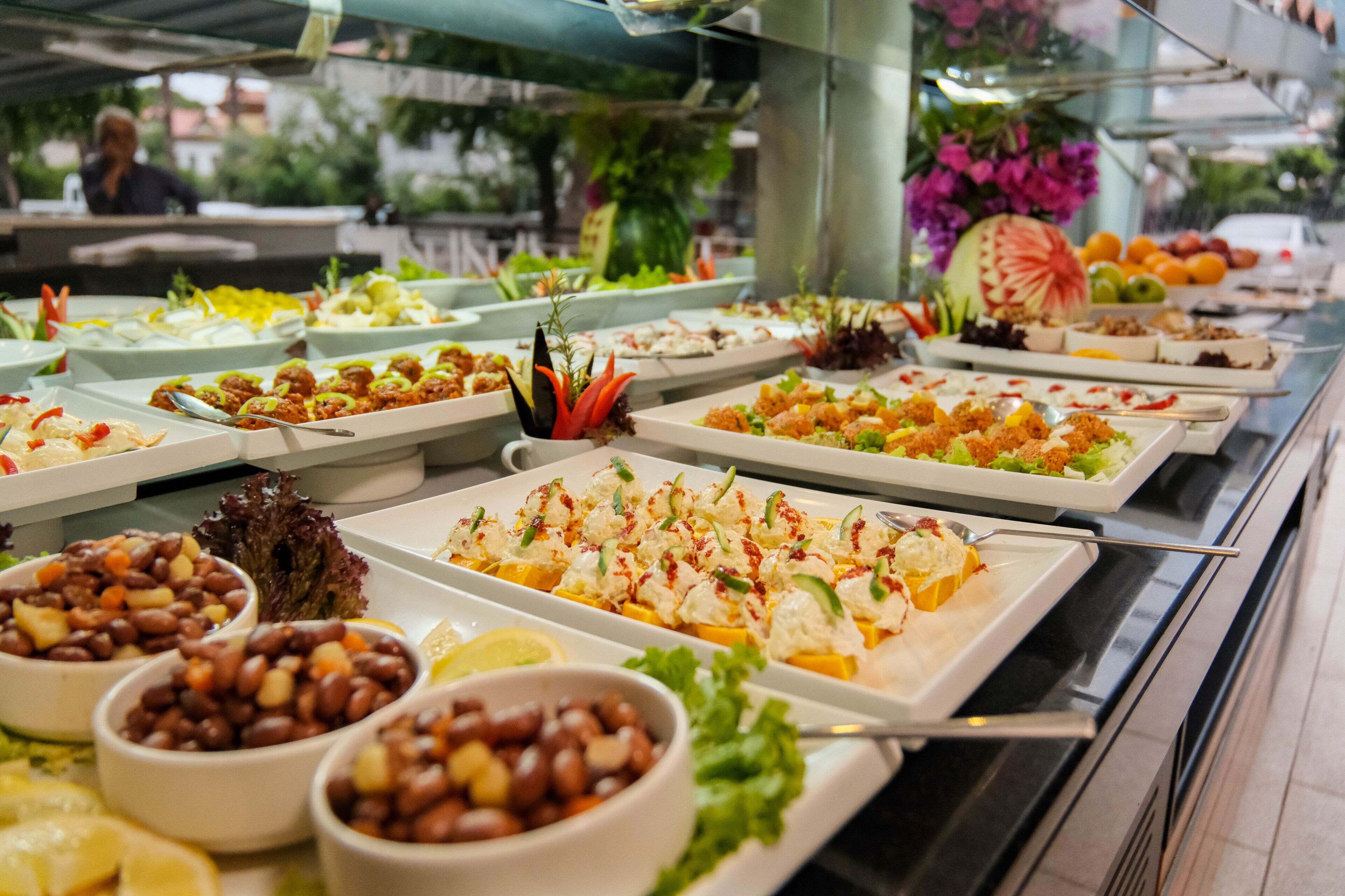 Un bufé con diversos platos, incluyendo ensaladas, frijoles y mariscos.