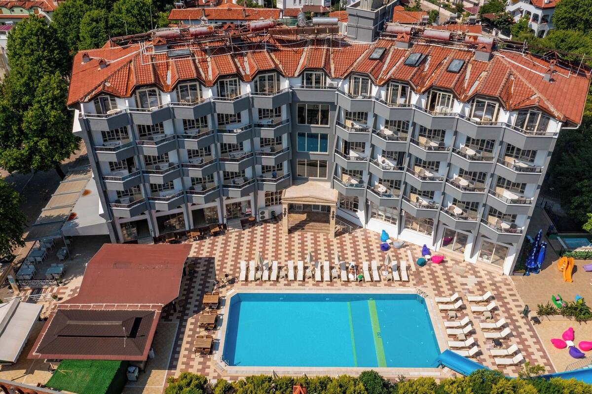 A multi-story hotel with a rooftop pool and a separate building with a smaller pool.