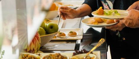 A buffet with various dishes and a person serving food.