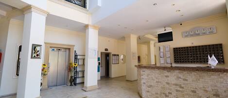 A spacious lobby with a reception desk, a staircase, and a balcony.