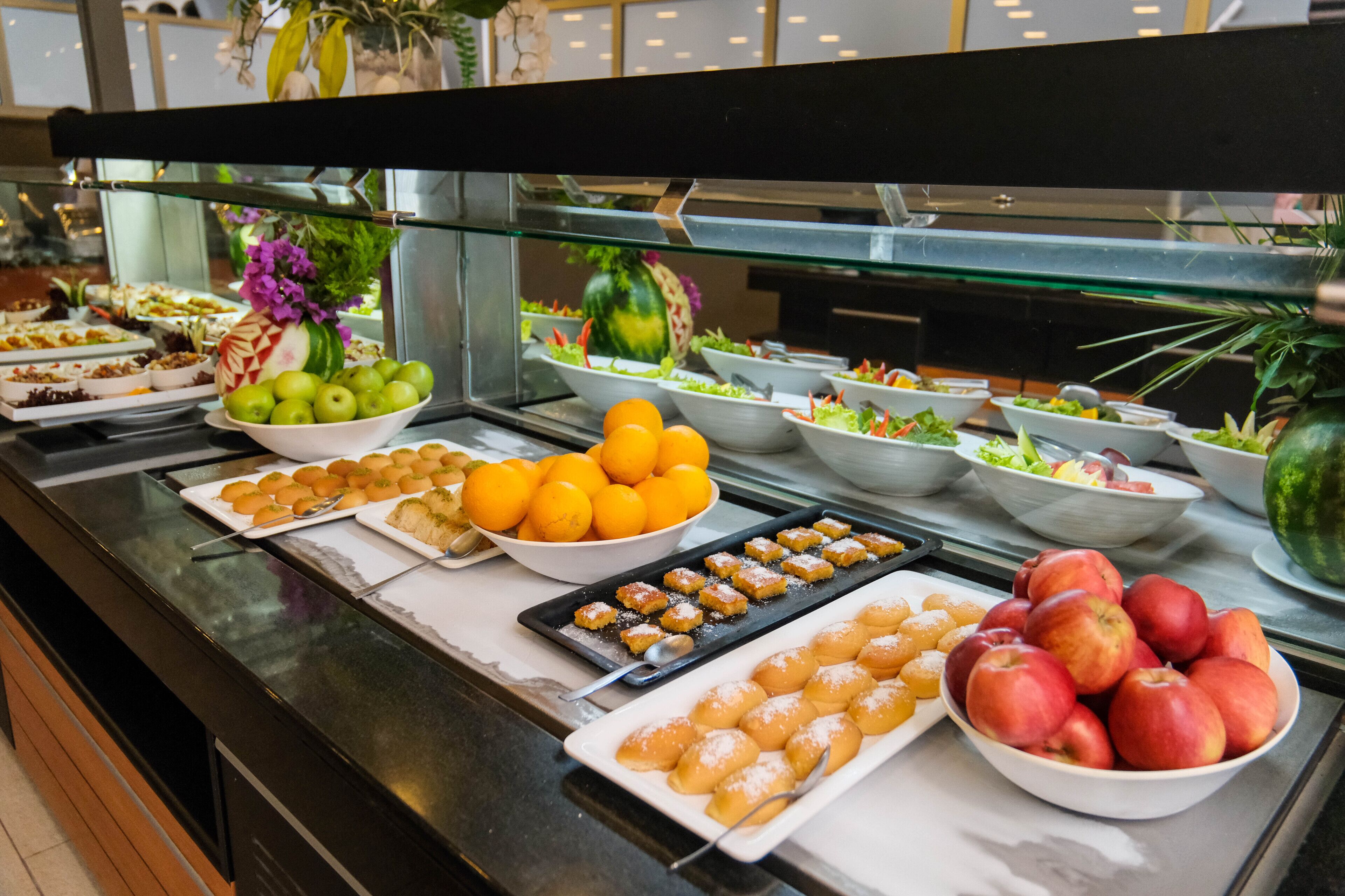 Buffet com diversos alimentos, incluindo frutas, saladas e sobremesas.