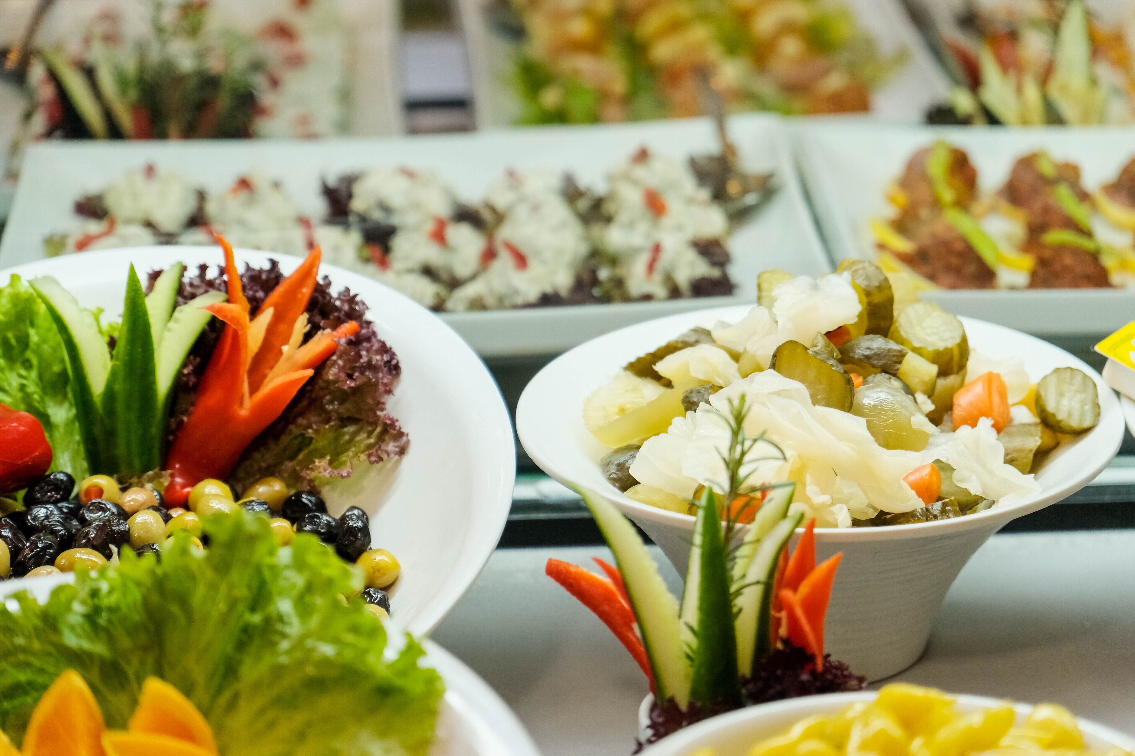 A buffet with various dishes including salads, fruits, and vegetables.
