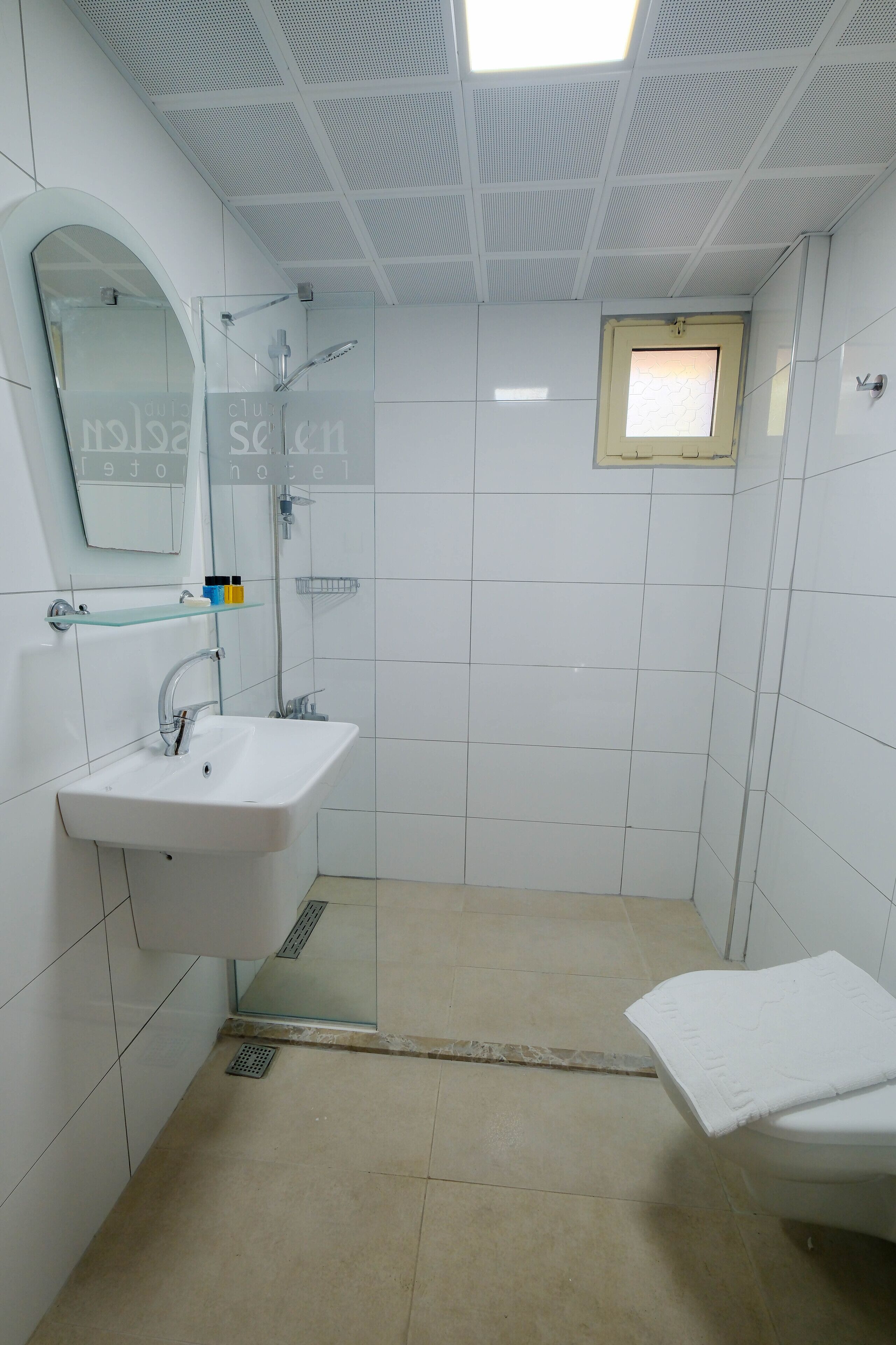 A modern bathroom with a white sink, mirror, and shower area.