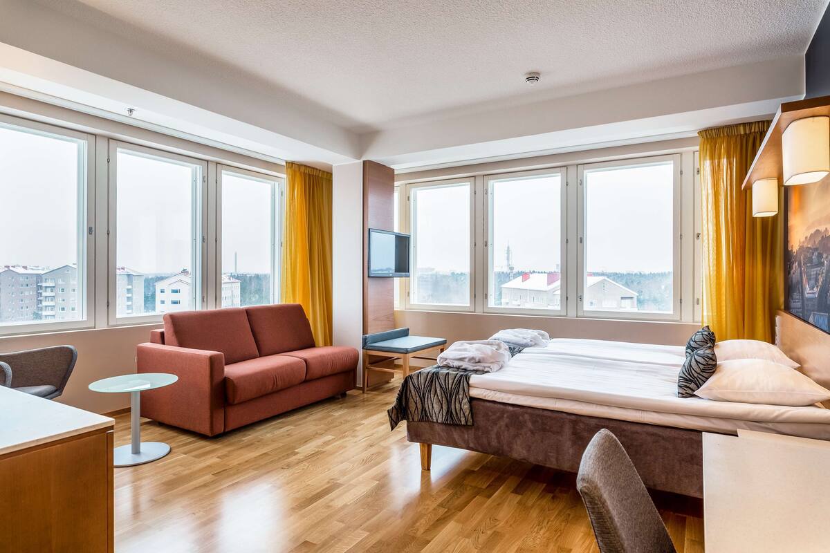 Une chambre d’hôtel moderne équipée d’un grand lit, d’un canapé, d’un bureau et d’une télévision.