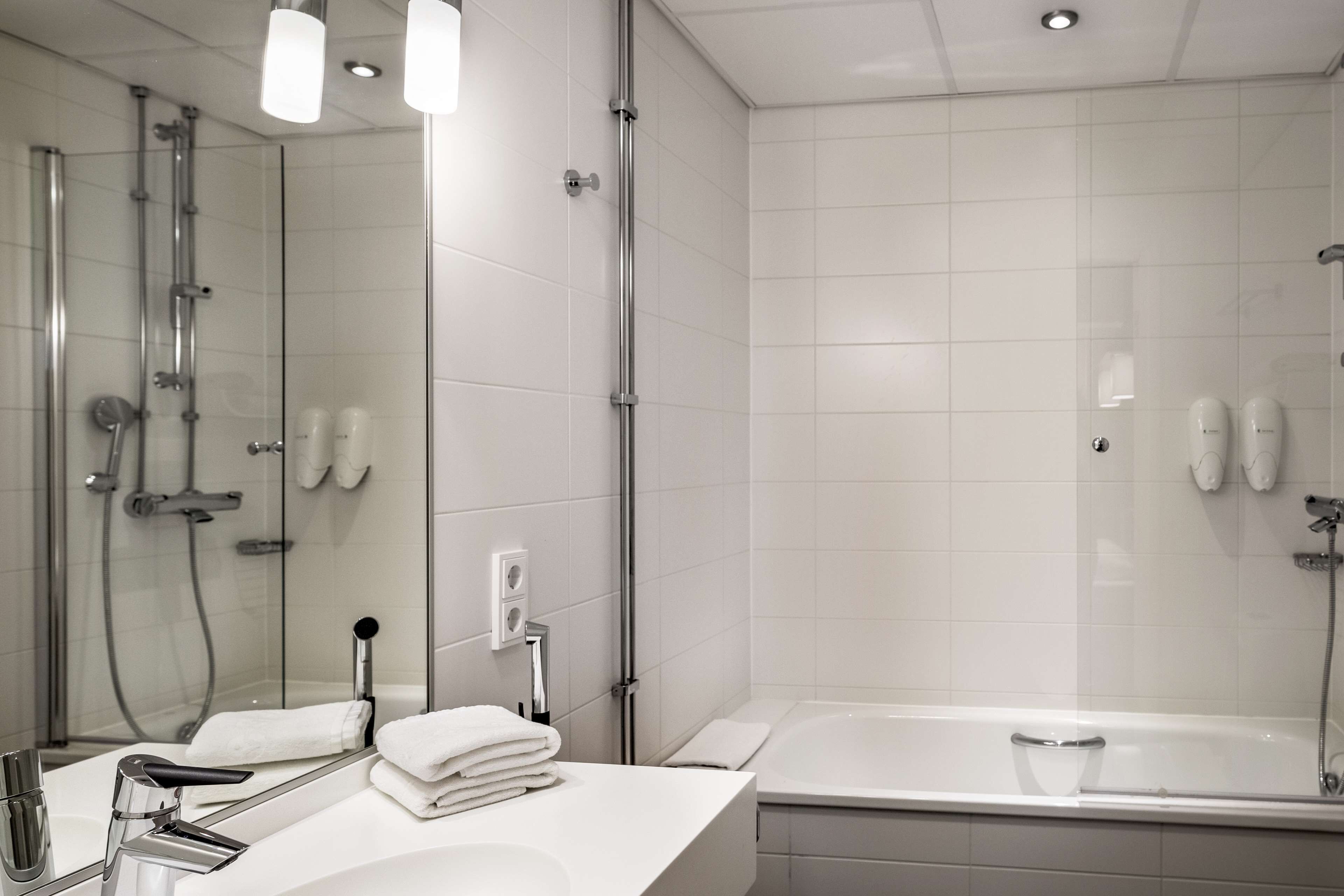 Un baño moderno con un espejo grande, una bañera y zona de ducha.