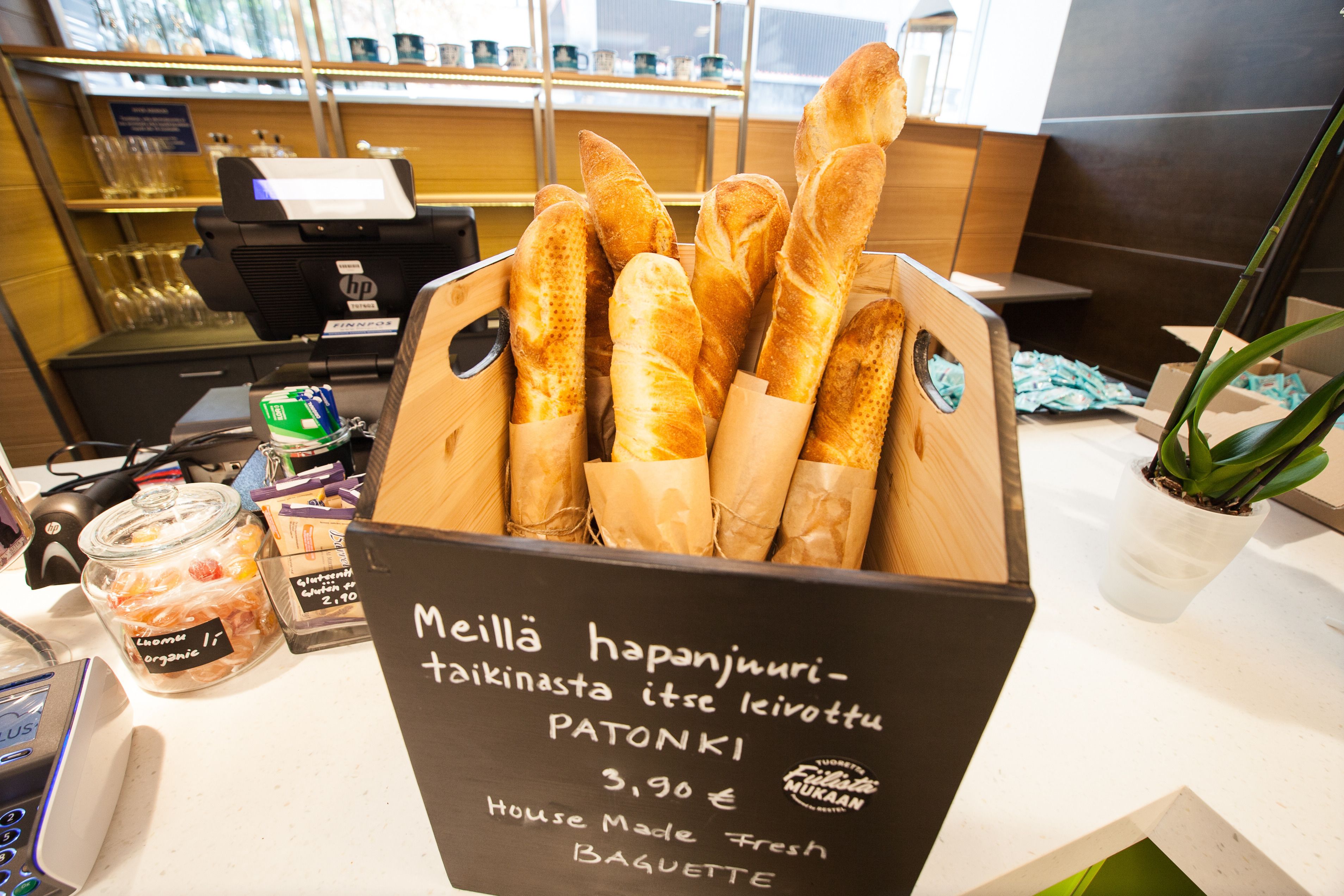 Une vitrine de boulangerie présentant des baguettes fraîchement cuites, avec une pancarte indiquant qu’elles sont faites sur place et préparées quotidiennement.