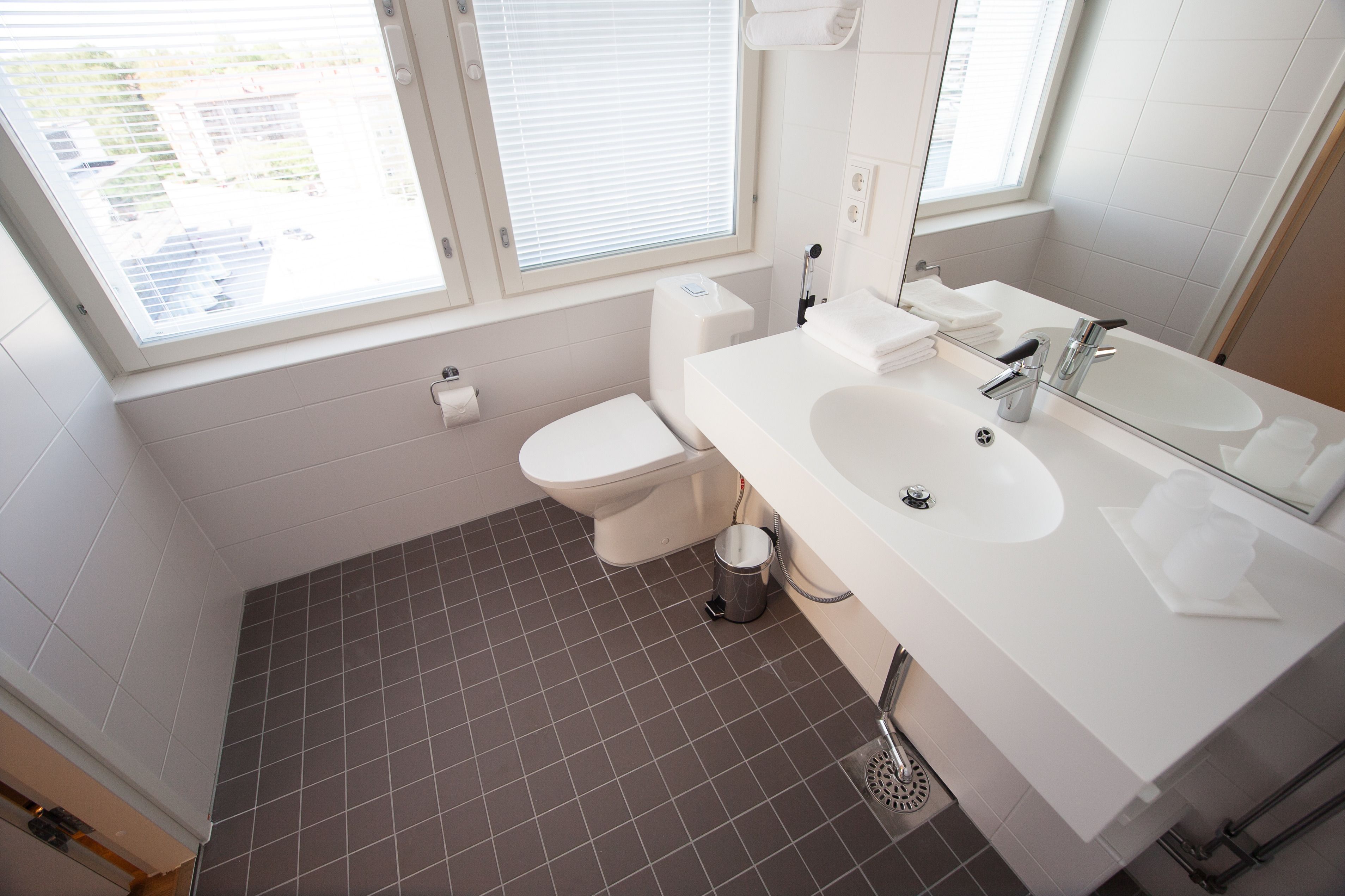 A modern bathroom with a toilet, sink, and window.