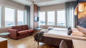 Una habitación de hotel moderna con una cama grande, un sofá, un escritorio y un televisor.