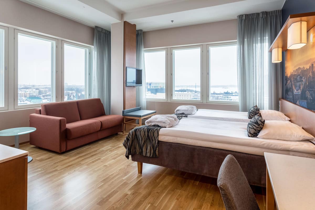 Une chambre d’hôtel moderne équipée d’un grand lit, d’un canapé, d’un bureau et d’une télévision.