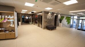 Un interior moderno con recepción, una cafetería llamada 'Bistro' y una escalera que sube a un piso superior.