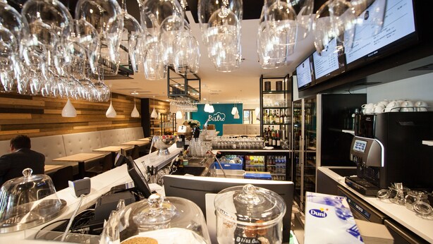 Un restaurante con zona de bar, bufé y máquina de café.