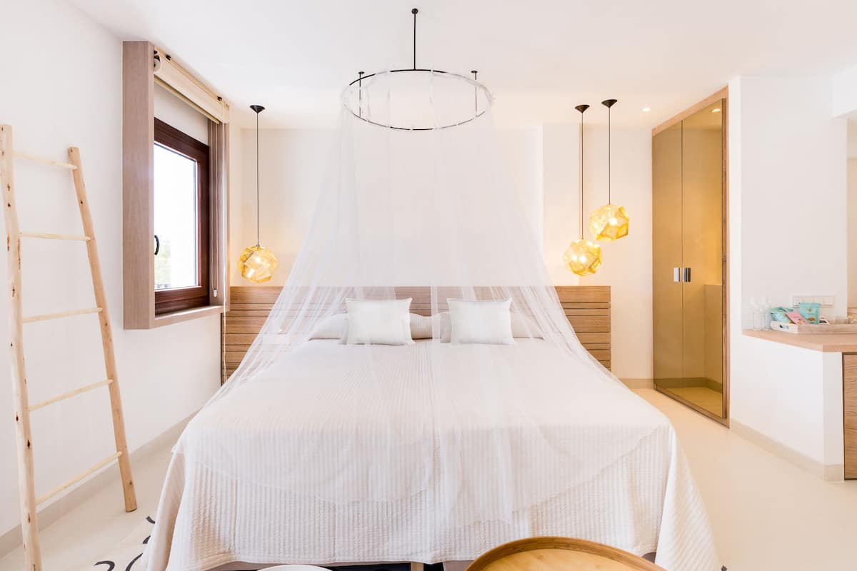 A modern bedroom with a large bed, a wooden ladder, a bedside table, and a wardrobe.