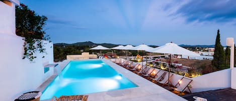 Una piscina al aire libre de temporada, sombrillas, tumbonas