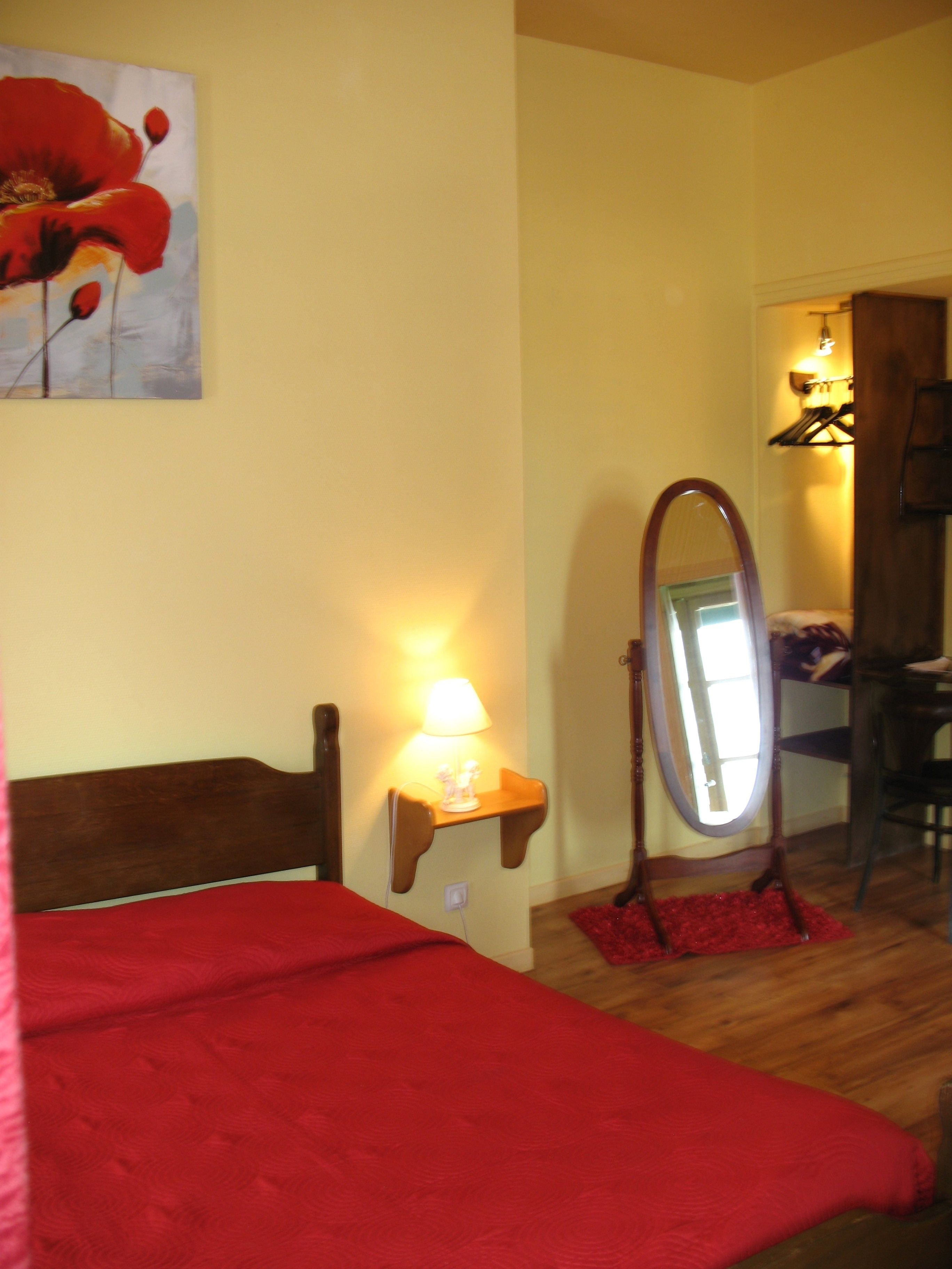 Une chambre à coucher avec un lit, une table de chevet avec une lampe, un miroir et une moquette rouge.