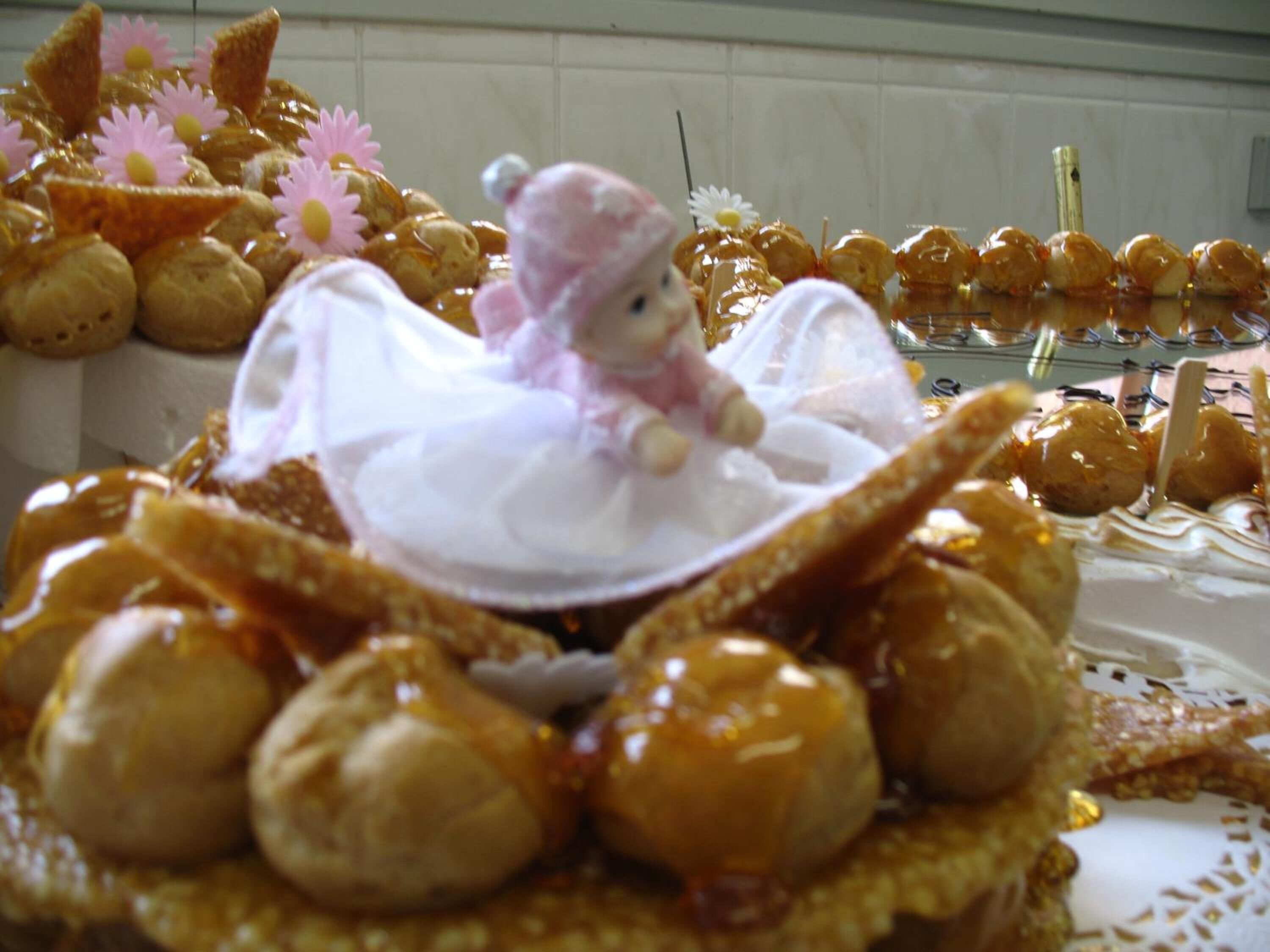 A dessert display with various sweets, including a doll in a white dress, surrounded by caramel-coated treats.