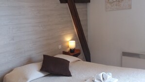 Una habitación de hotel con cama, mesita de noche con lámpara, almohada y una obra de arte colgada en la pared.