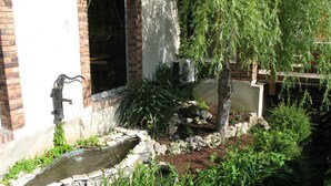 Un jardín con fuente de agua, muros de piedra y diversas plantas.
