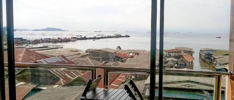 A view from a balcony overlooking a coastal area with buildings and a pier.