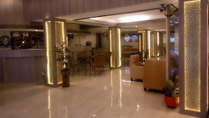 A spacious, well-lit hotel lobby with a modern design, featuring a bar area, seating arrangements, and a reception desk. - Seaview Sriracha Hotel (Si Racha)