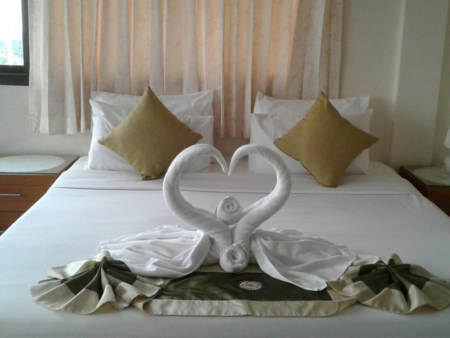 Une chambre d’hôtel avec un lit bien fait, deux oreillers et un cygne décoratif réalisé avec des serviettes.
