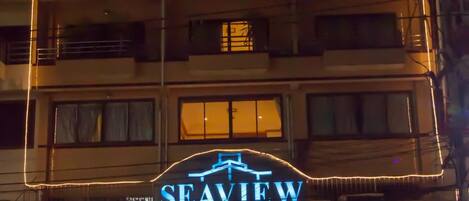 A building with a neon sign reading "SEAVIEW" and a restaurant with outdoor seating.