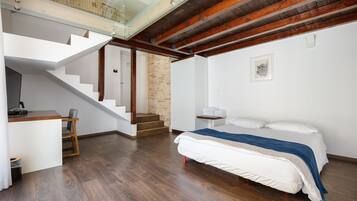 Une chambre moderne avec un grand lit, un bureau et un escalier menant à un niveau supérieur.