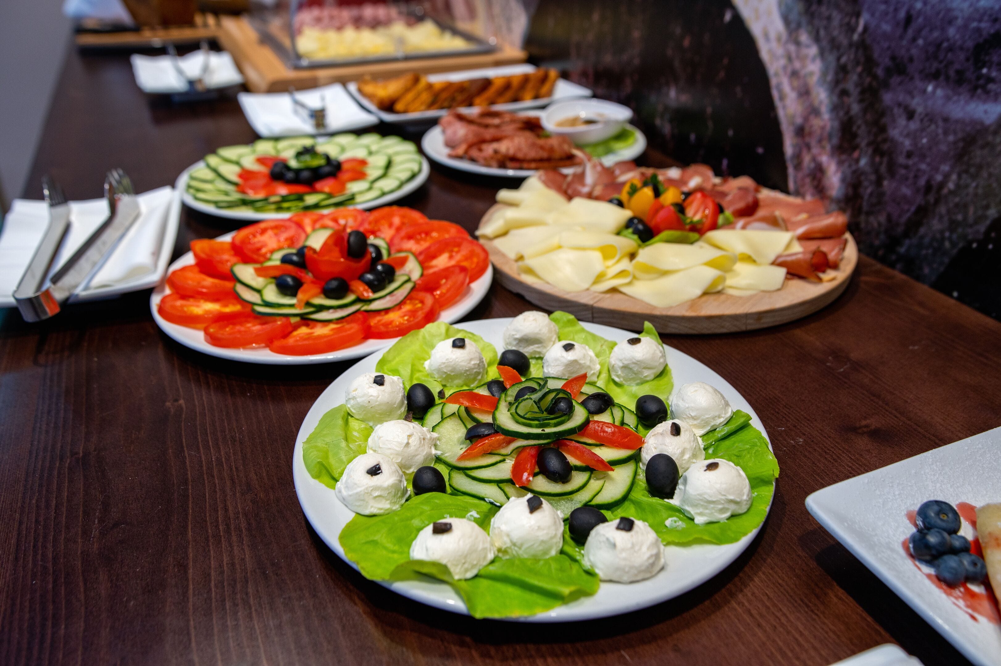 Una mesa con varios platos de comida, incluyendo ensaladas, quesos y carnes.