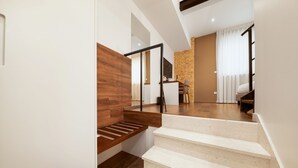 A modern staircase with wooden and white steps, leading to a living area with a TV, a sofa, and a dining table. - Azur Palace Luxury Rooms (Split)