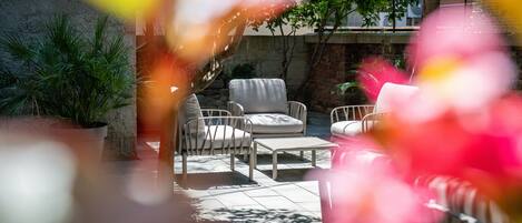A patio area with outdoor furniture, including a sofa and chairs, a small table, and a potted plant.