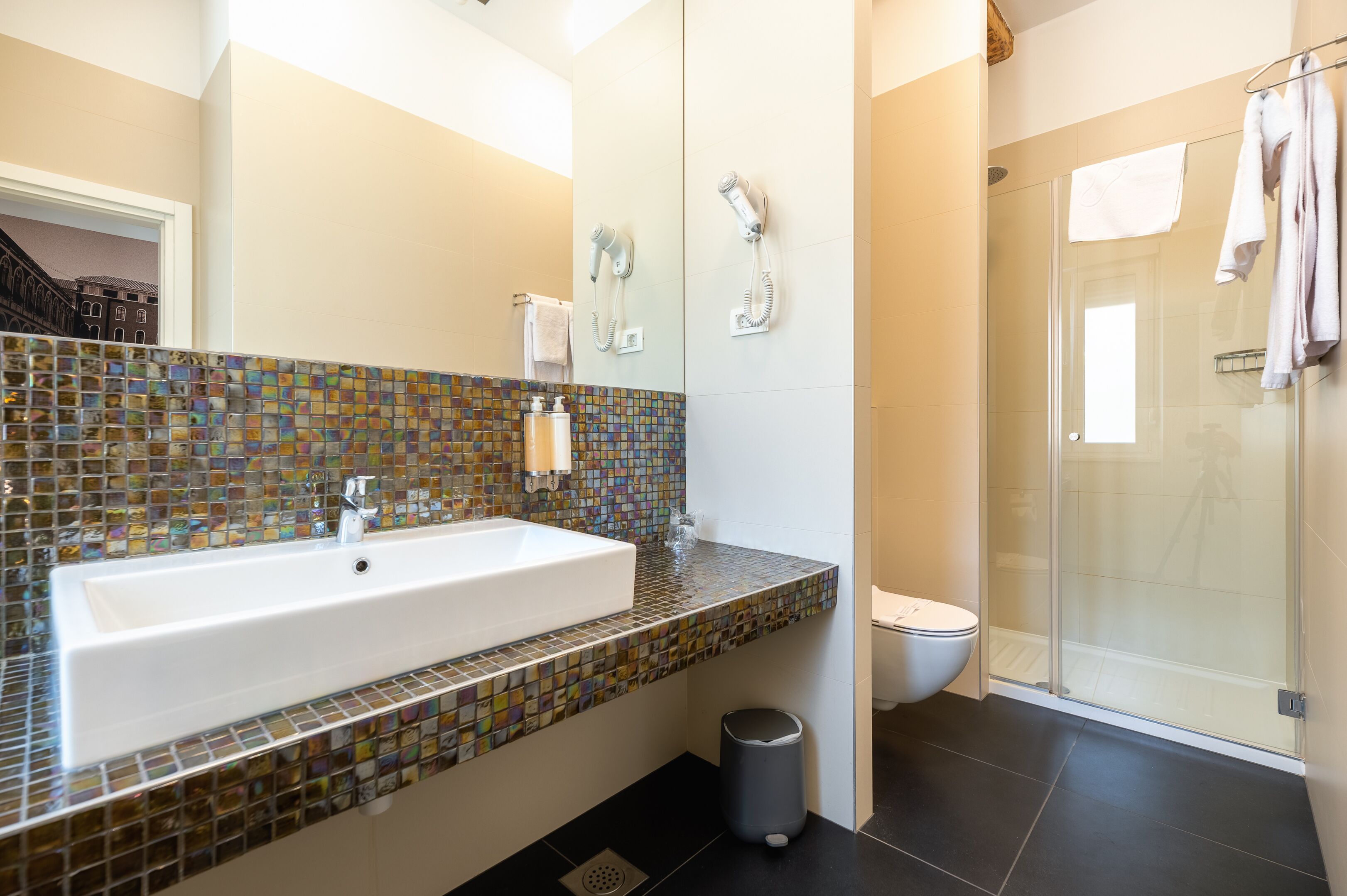 Un baño con un lavamanos grande, ducha y zona de ducha con mampara de vidrio.