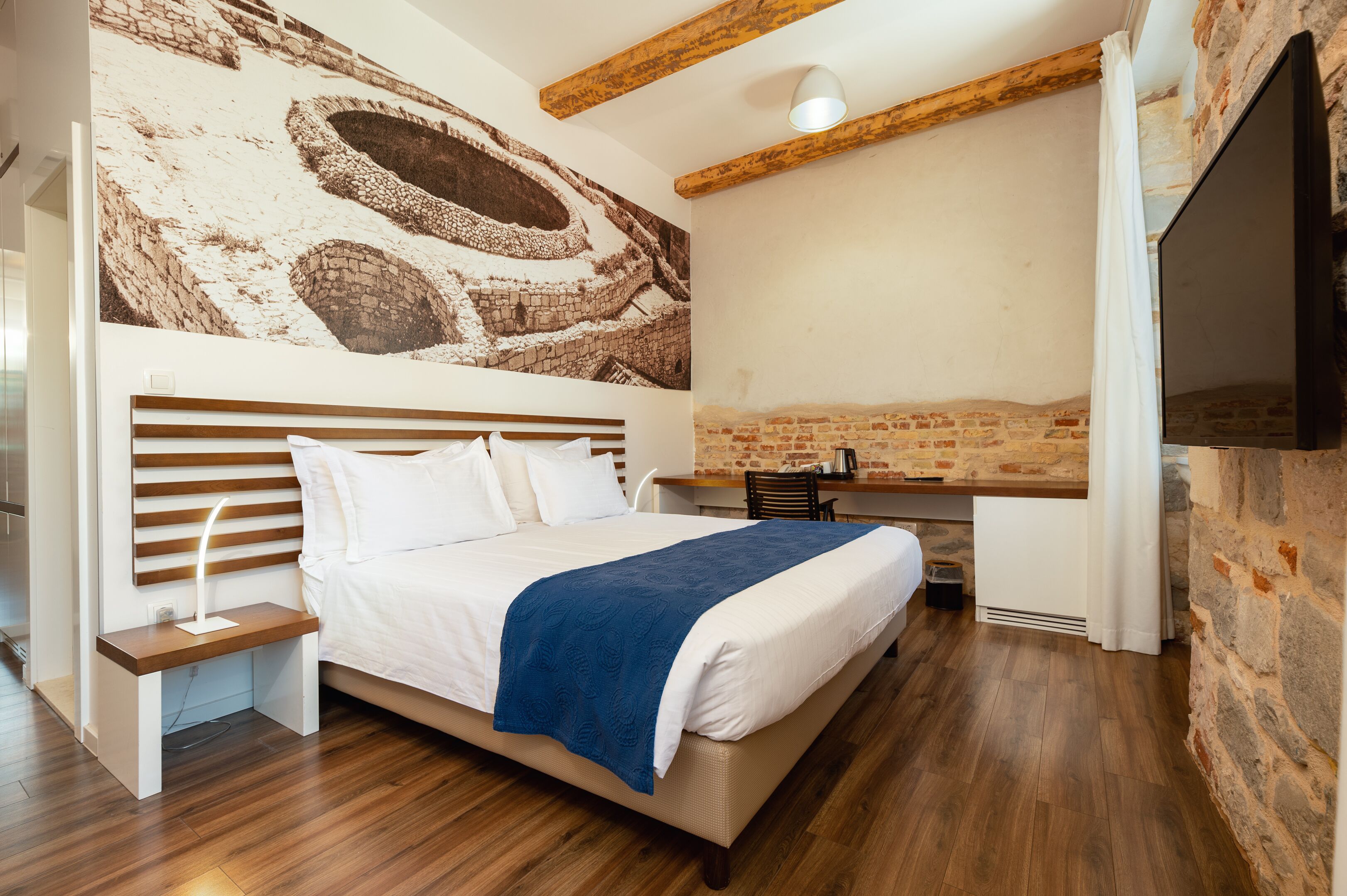 Un dormitorio con una cama grande, un escritorio y un televisor.